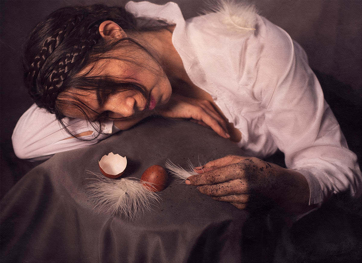 photograph of a woman at a table with eggs and feathers